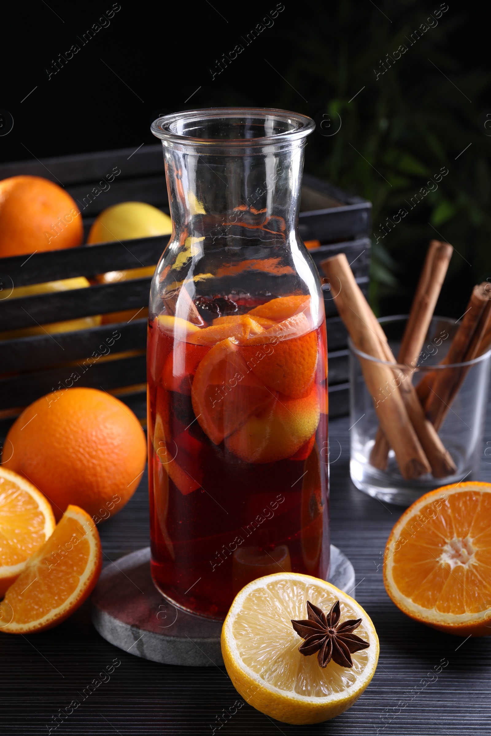 Photo of Aromatic punch drink and ingredients on black table