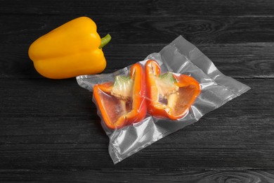 Photo of Bell pepper in vacuum pack and separately on black wooden table, closeup
