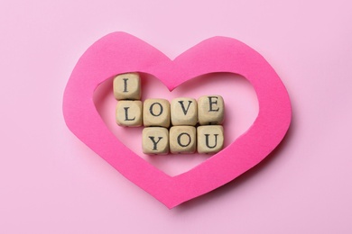 Photo of Phrase I Love You made of cubes and paper heart on pink background, flat lay