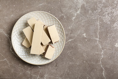 Photo of Plate of delicious crispy wafers with chocolate filling on grey stone table, top view. Space for text