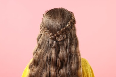 Little girl with braided hair on pink background, back view