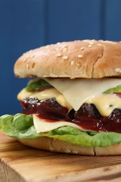 Photo of Tasty homemade cheeseburger with lettuce on wooden board, closeup