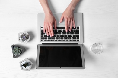 Photo of Woman using laptop at white wooden table, closeup of hands. Space for text
