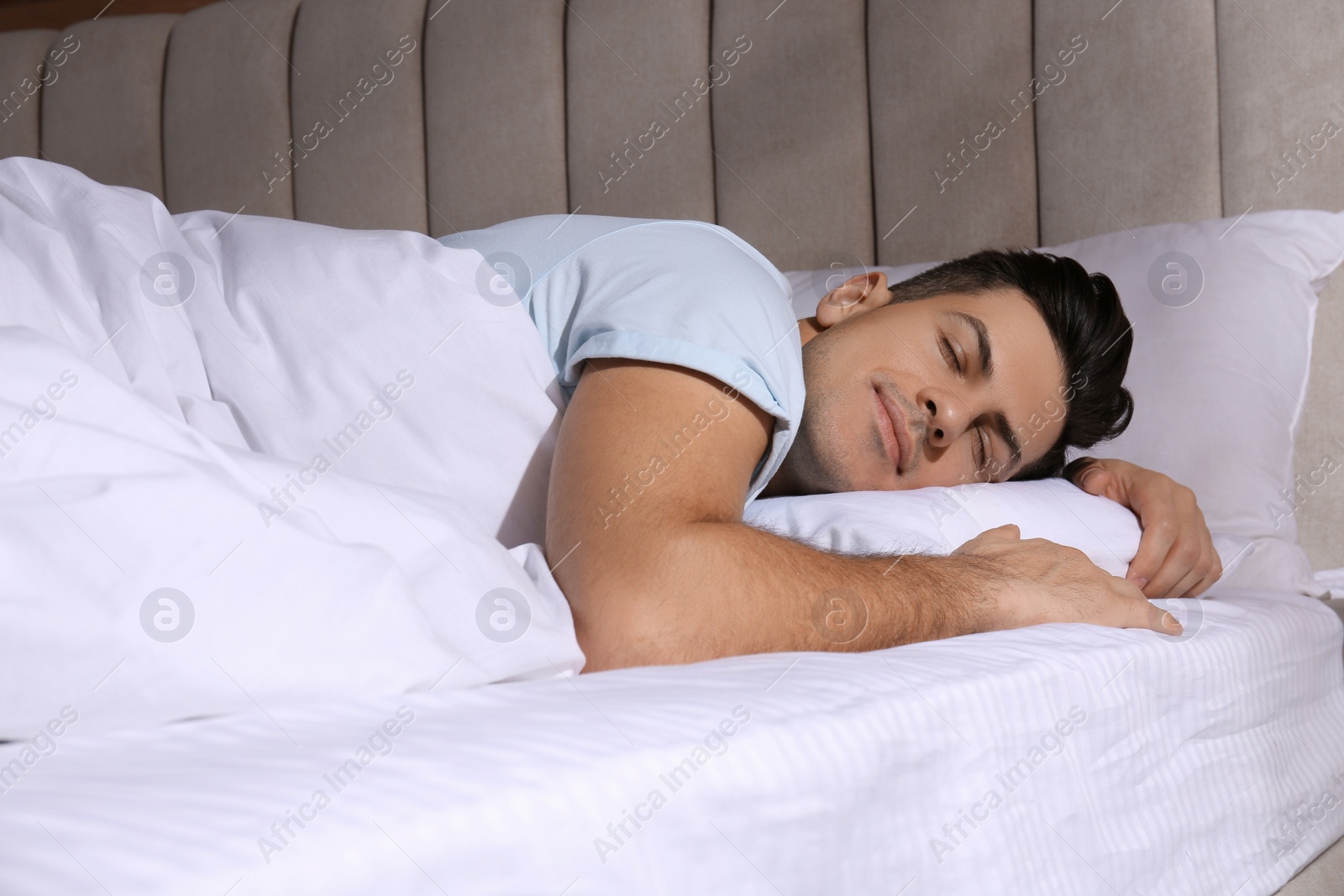 Photo of Man sleeping in comfortable bed with white linens