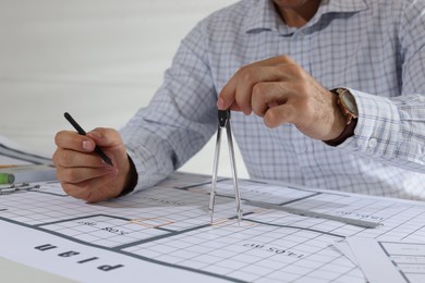 Photo of Architect working with construction drawings indoors, closeup