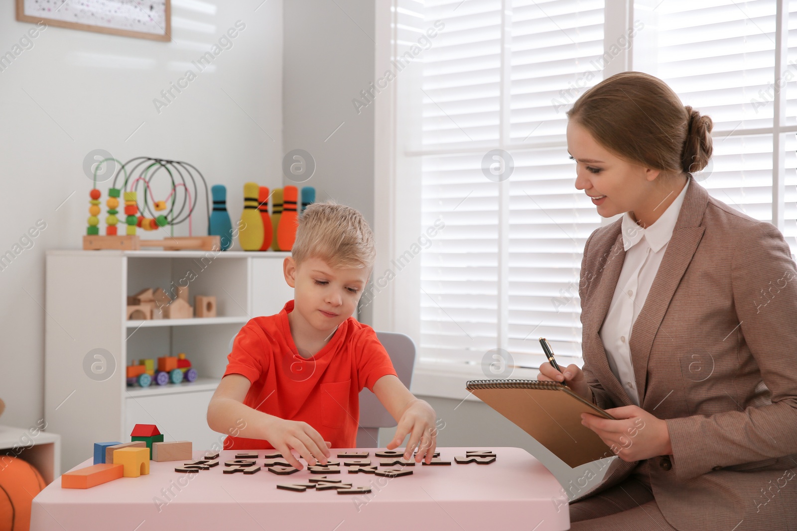 Photo of Speech therapist working with little boy in office