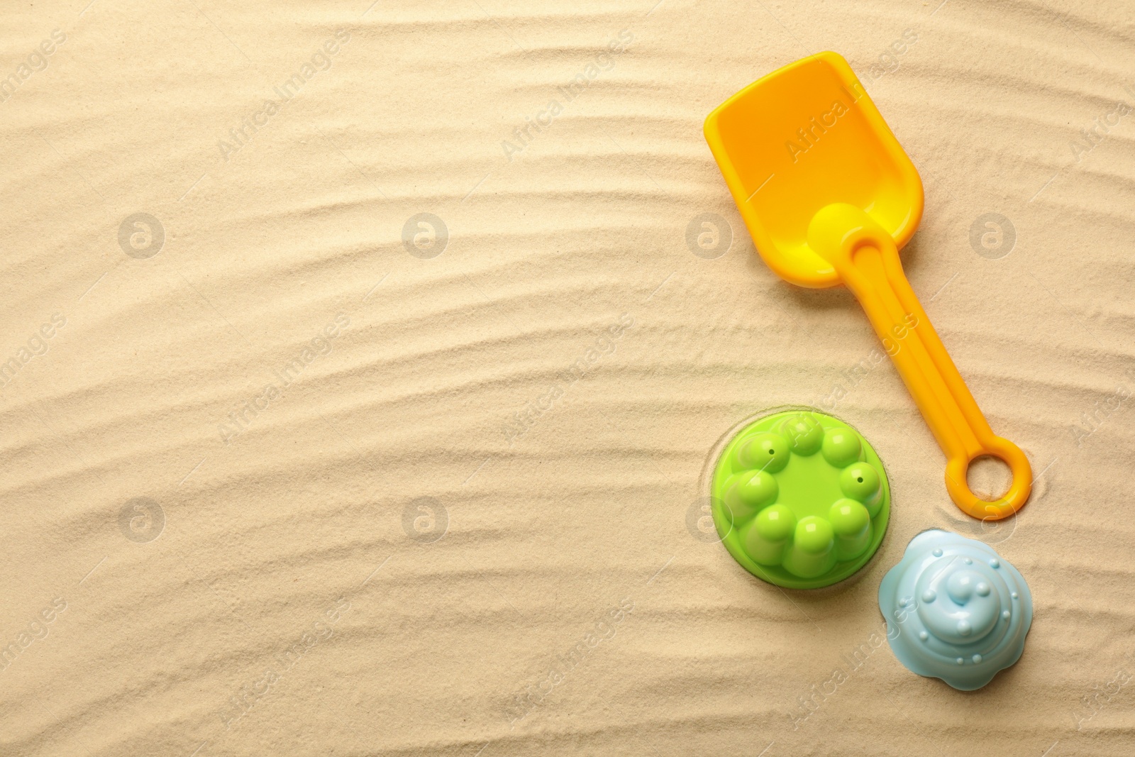 Photo of Flat lay of beach toy kit on sand, space for text. Outdoor play