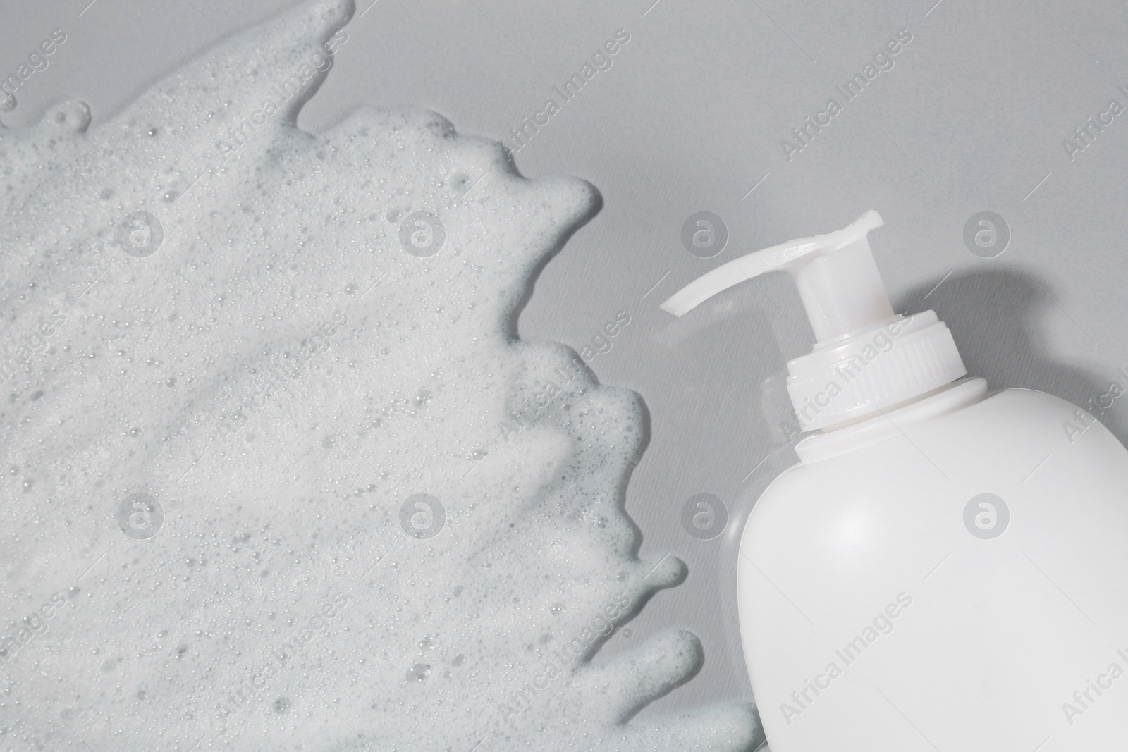 Photo of Dispenser with cleansing foam on light grey background, top view. Cosmetic product