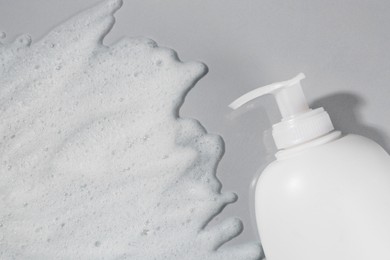 Dispenser with cleansing foam on light grey background, top view. Cosmetic product