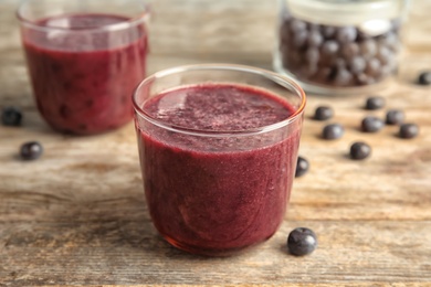 Photo of Glasses with delicious acai smoothie on wooden table