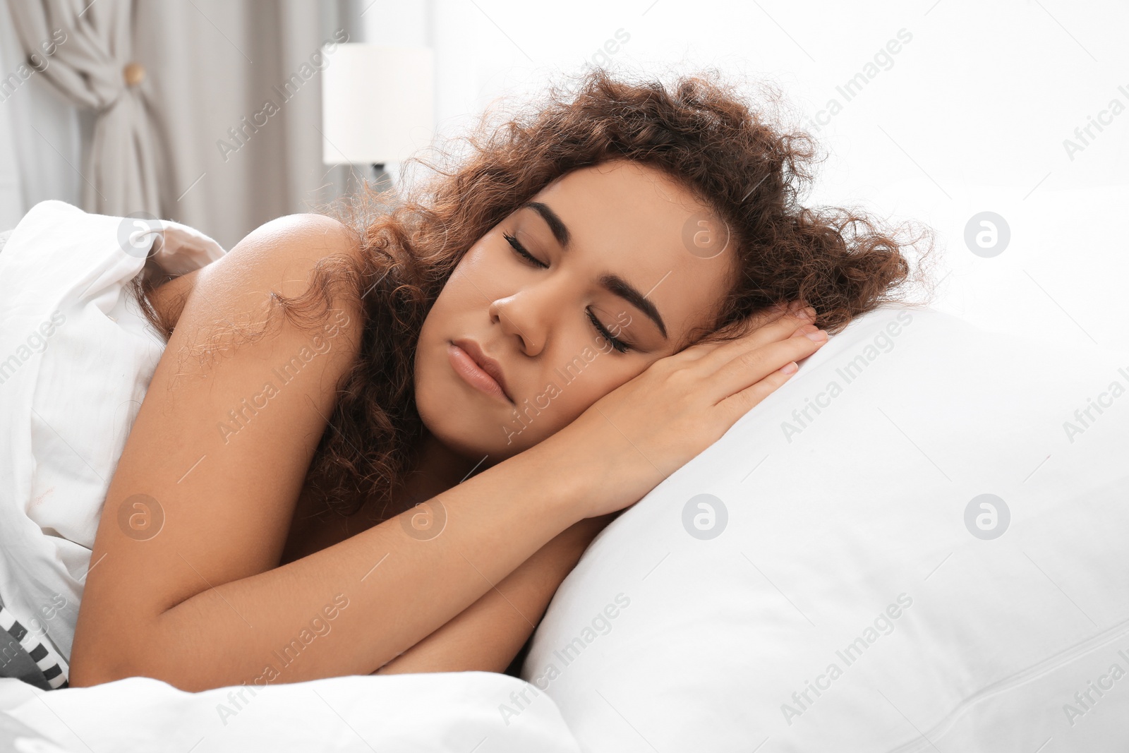 Photo of Young African-American woman sleeping on soft pillow at home. Bedtime