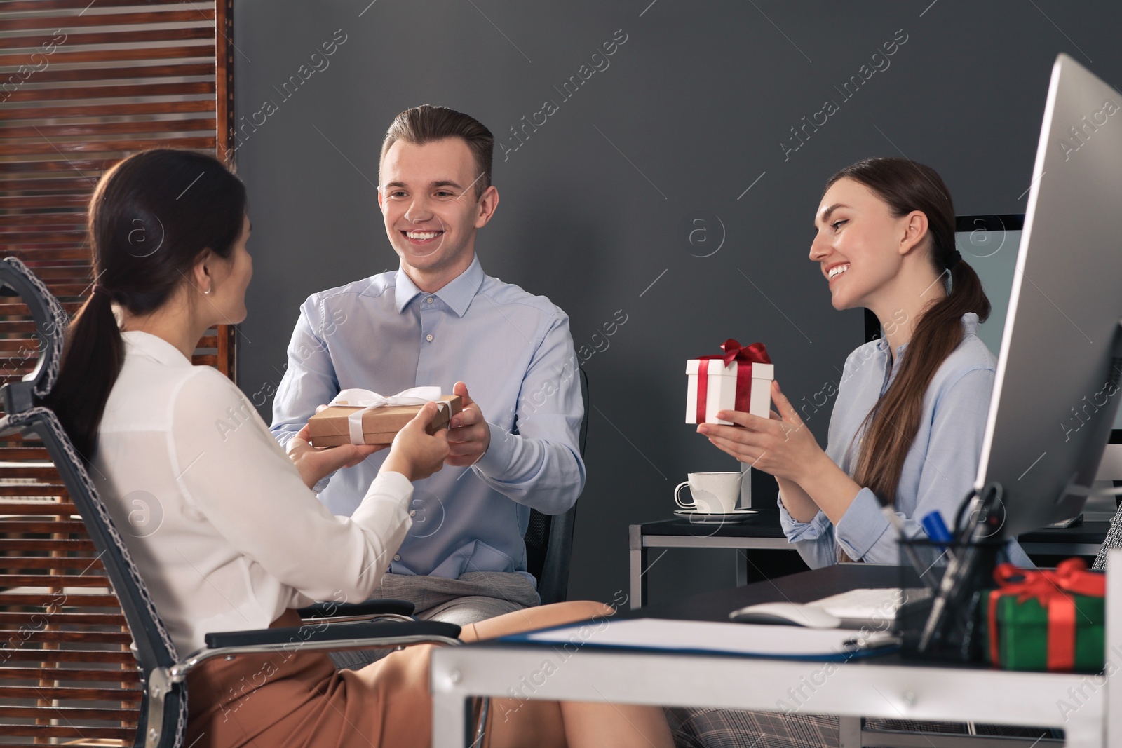 Photo of Colleagues presenting gifts to woman in office