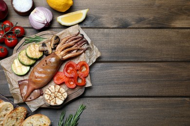 Photo of Tasty grilled squid served on wooden table, flat lay. Space for text