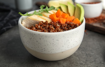 Cooked quinoa with garnish in bowl on table