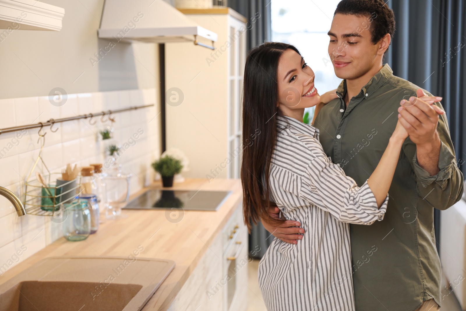 Photo of Lovely young interracial couple dancing at home. Space for text