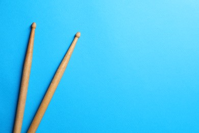 Photo of Two wooden drum sticks on light blue background, top view. Space for text