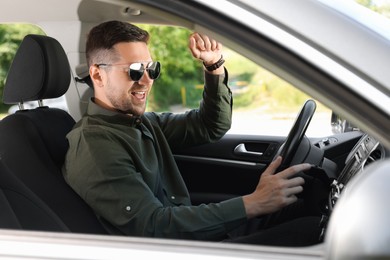 Choosing favorite radio. Man with sunglasses enjoying music in car