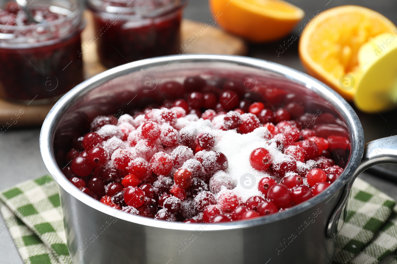 Photo of Making cranberry sauce. Fresh cranberries with sugar in saucepan on table, closeup