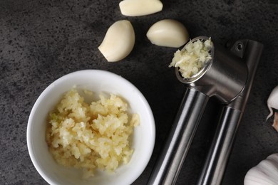 Garlic press, cloves and mince on grey table, flat lay