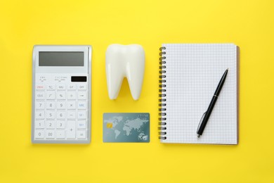 Photo of Flat lay composition with ceramic model of tooth and credit card on yellow background. Expensive treatment