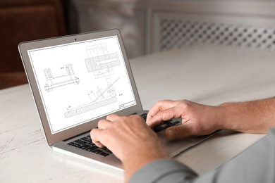 Image of Male engineer working with technical drawing on laptop indoors, closeup
