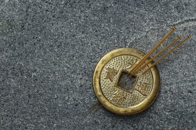 Acupuncture needles and Chinese coin on grey textured table, top view. Space for text