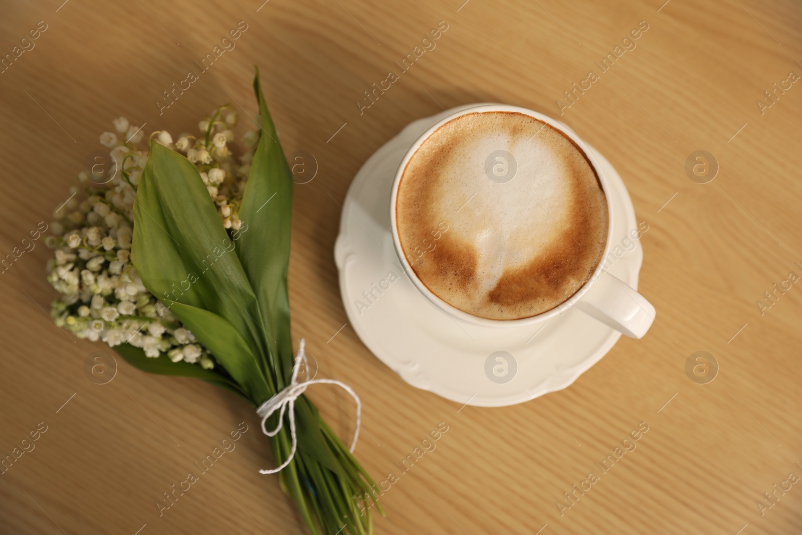 Photo of Cup of aromatic morning coffee on wooden table, above view