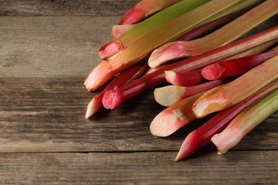 Photo of Stalks of fresh ripe rhubarb on wooden table, space for text