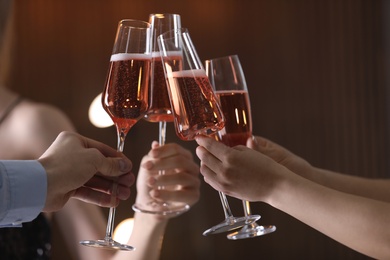Photo of Friends clinking glasses with champagne on blurred background, closeup