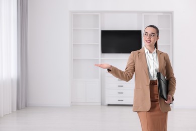 Photo of Happy real estate agent with leather portfolio showing new apartment. Space for text