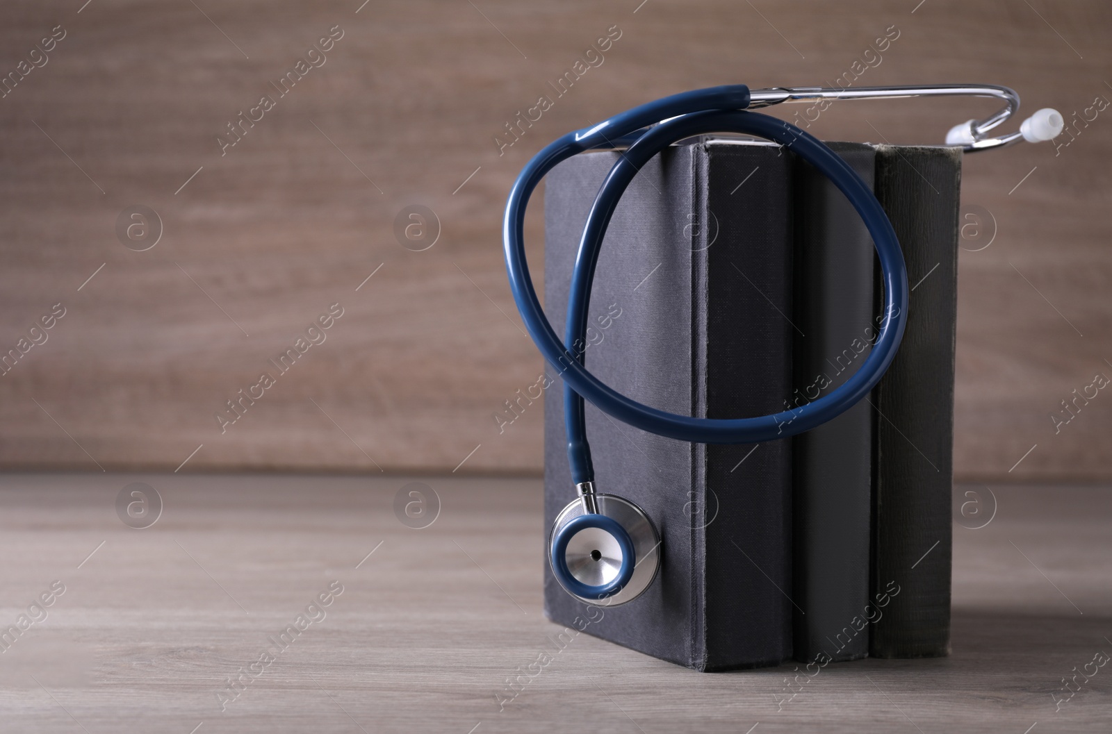 Photo of Student textbooks and stethoscope on wooden table, space for text. Medical education