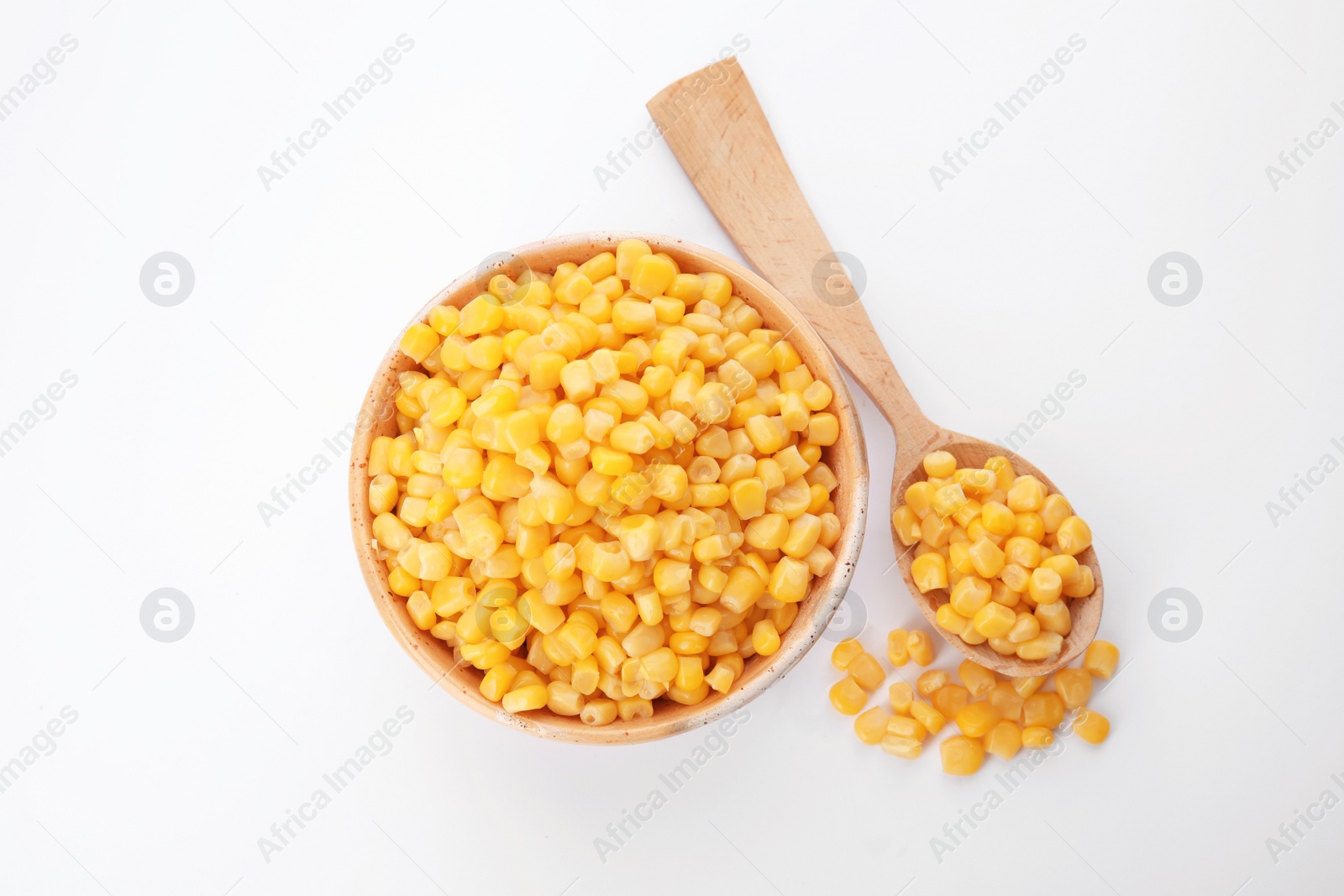 Photo of Bowl and spoon with corn kernels on white background, top view