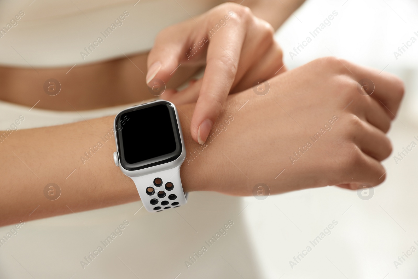 Photo of Young woman using smart watch during training indoors, closeup