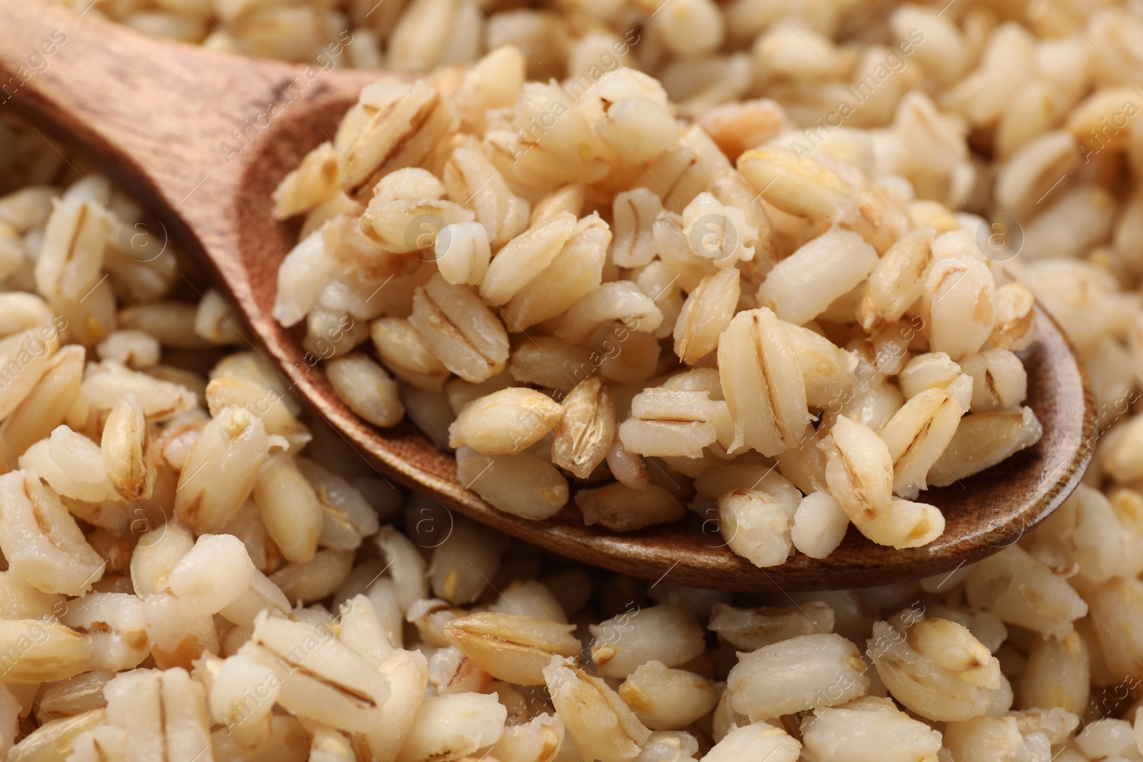 Photo of Delicious pearl barley and wooden spoon, closeup