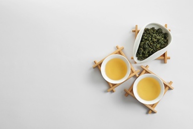 Photo of Cups of Tie Guan Yin and chahe with tea leaves on white background, top view