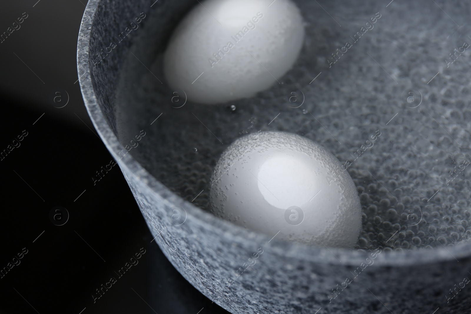 Photo of Chicken eggs boiling in saucepan on electric stove, closeup