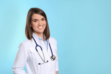 Pediatrician with stethoscope on light blue background, space for text