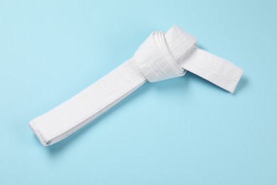 Photo of White karate belt on light blue background, top view