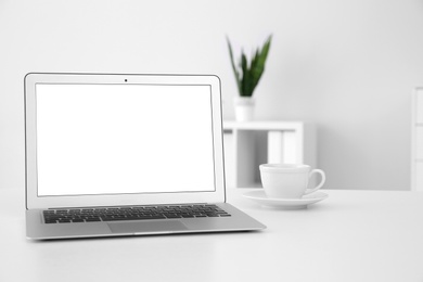 Comfortable workplace with modern laptop on table in office. Mockup for design