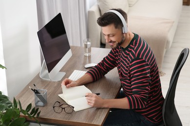 Photo of Man in headphones studying near computer at home. Online translation course