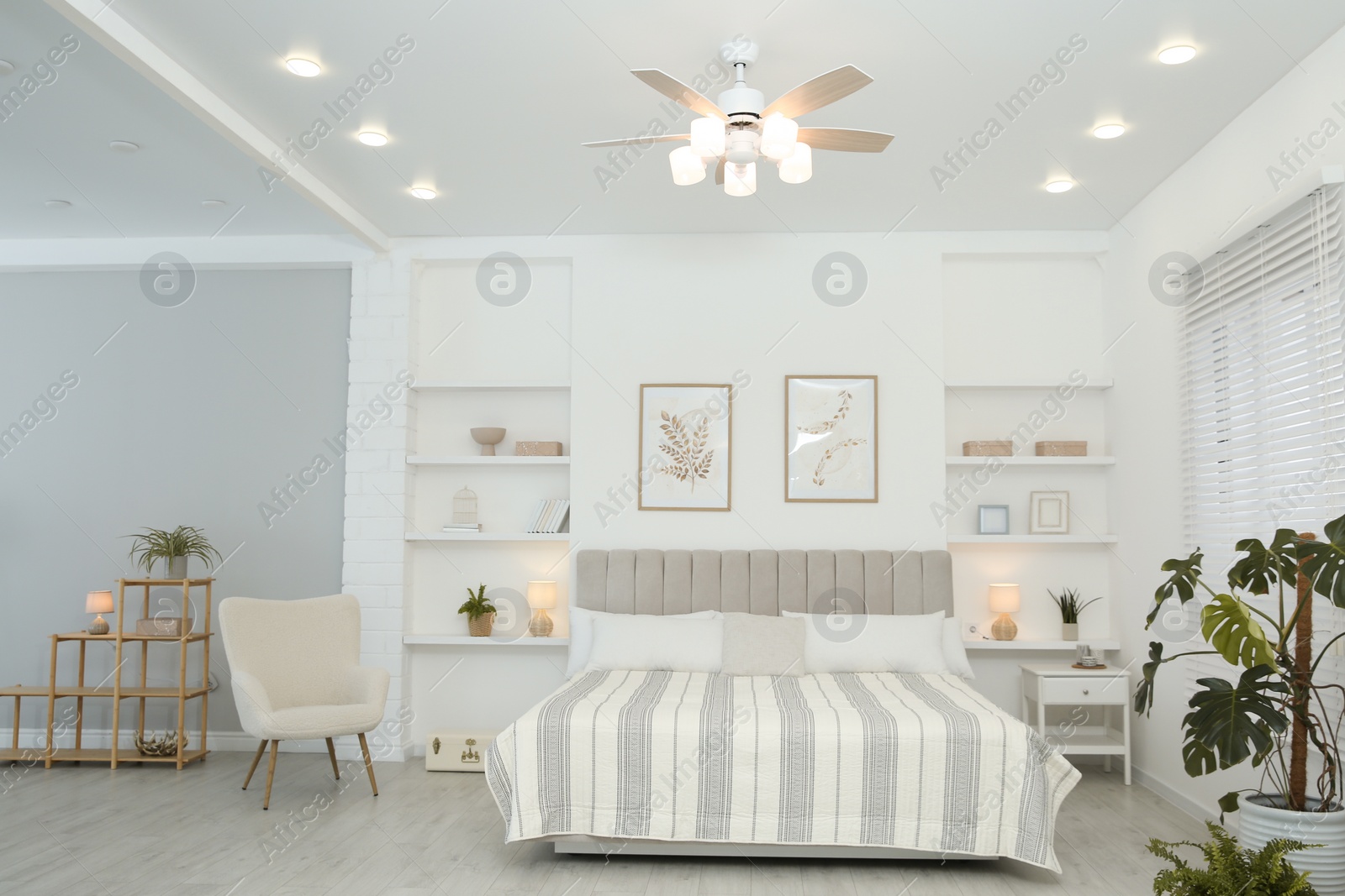 Photo of Comfortable furniture, ceiling fan, houseplants and accessories in stylish bedroom