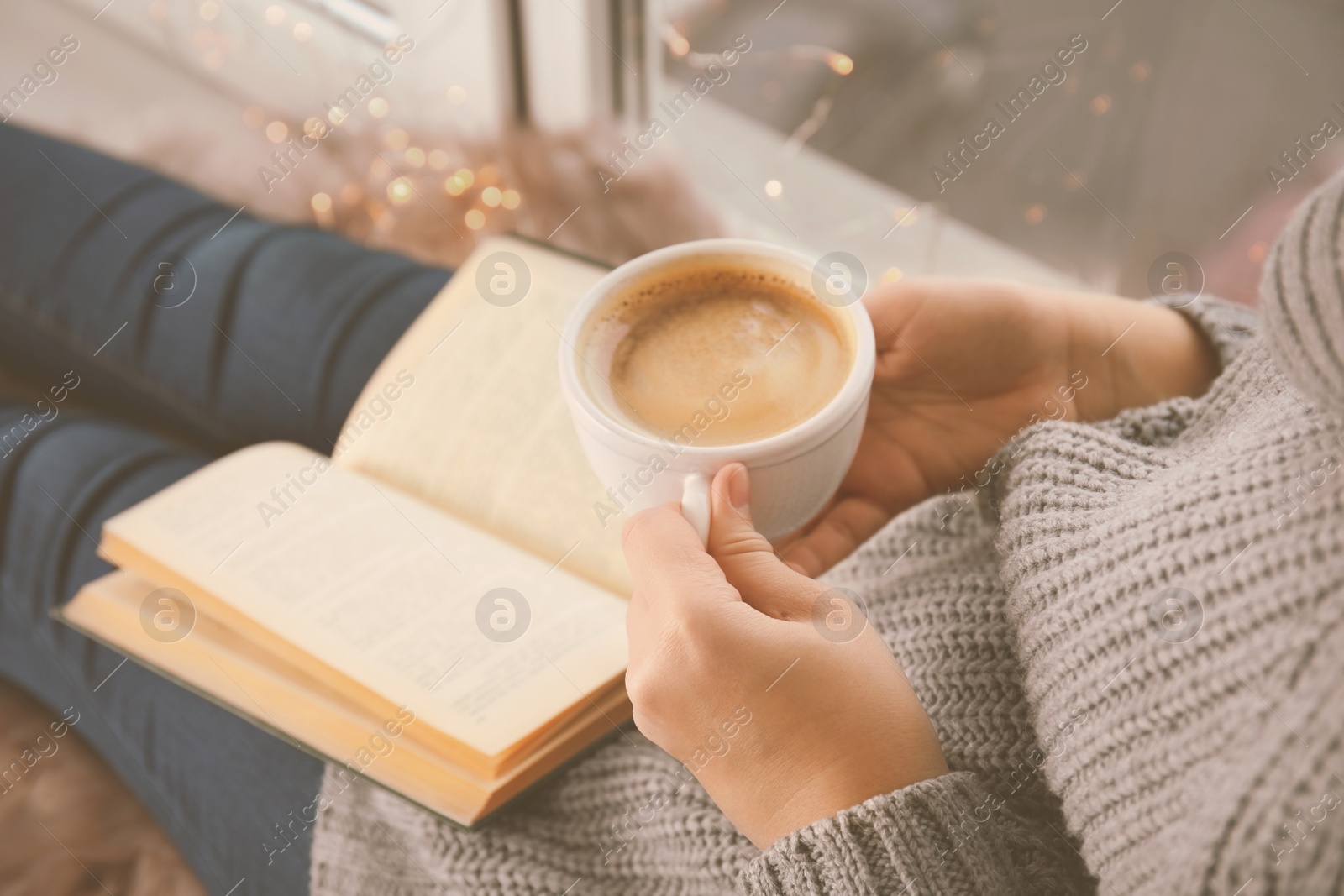 Image of Woman with cup of coffee reading book at home, closeup