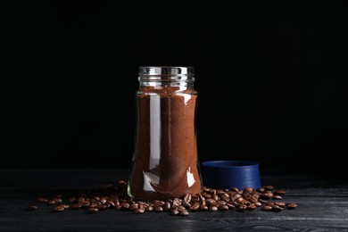 Glass jar with aromatic ground coffee and beans on black wooden table