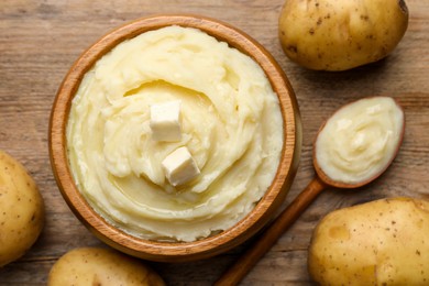 Bowl of delicious mashed potato with butter on wooden table, flat lay