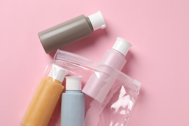 Photo of Plastic bag with cosmetic travel kit on pink background, flat lay. Bath accessories