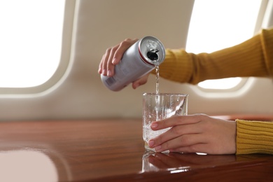 Image of Woman pouring water on plane, closeup. Comfortable flight