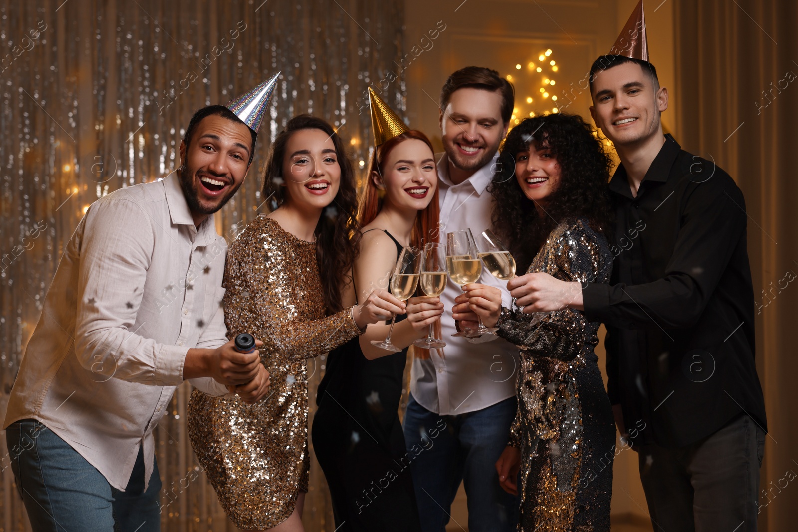 Photo of Happy friends clinking glasses of sparkling wine at birthday party indoors