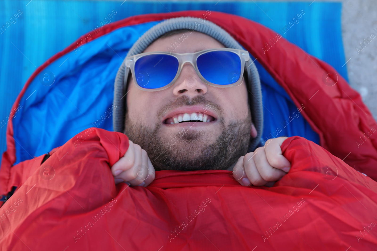 Photo of Male camper lying in sleeping bag on mat, view from above