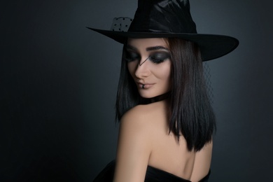 Photo of Mysterious witch wearing hat on black background