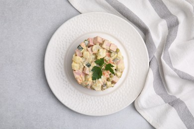 Photo of Tasty Olivier salad with boiled sausage on light grey table, top view